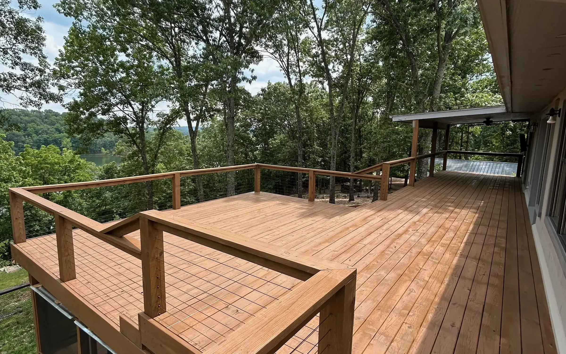 Wide ipe deck with wire rail and lake hillside view