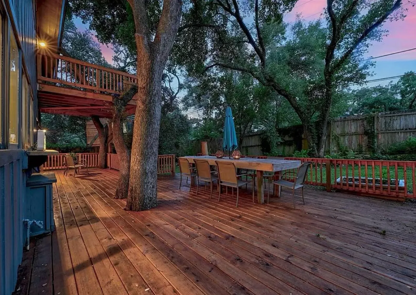 Deck dining area under a tree canopy at twilight