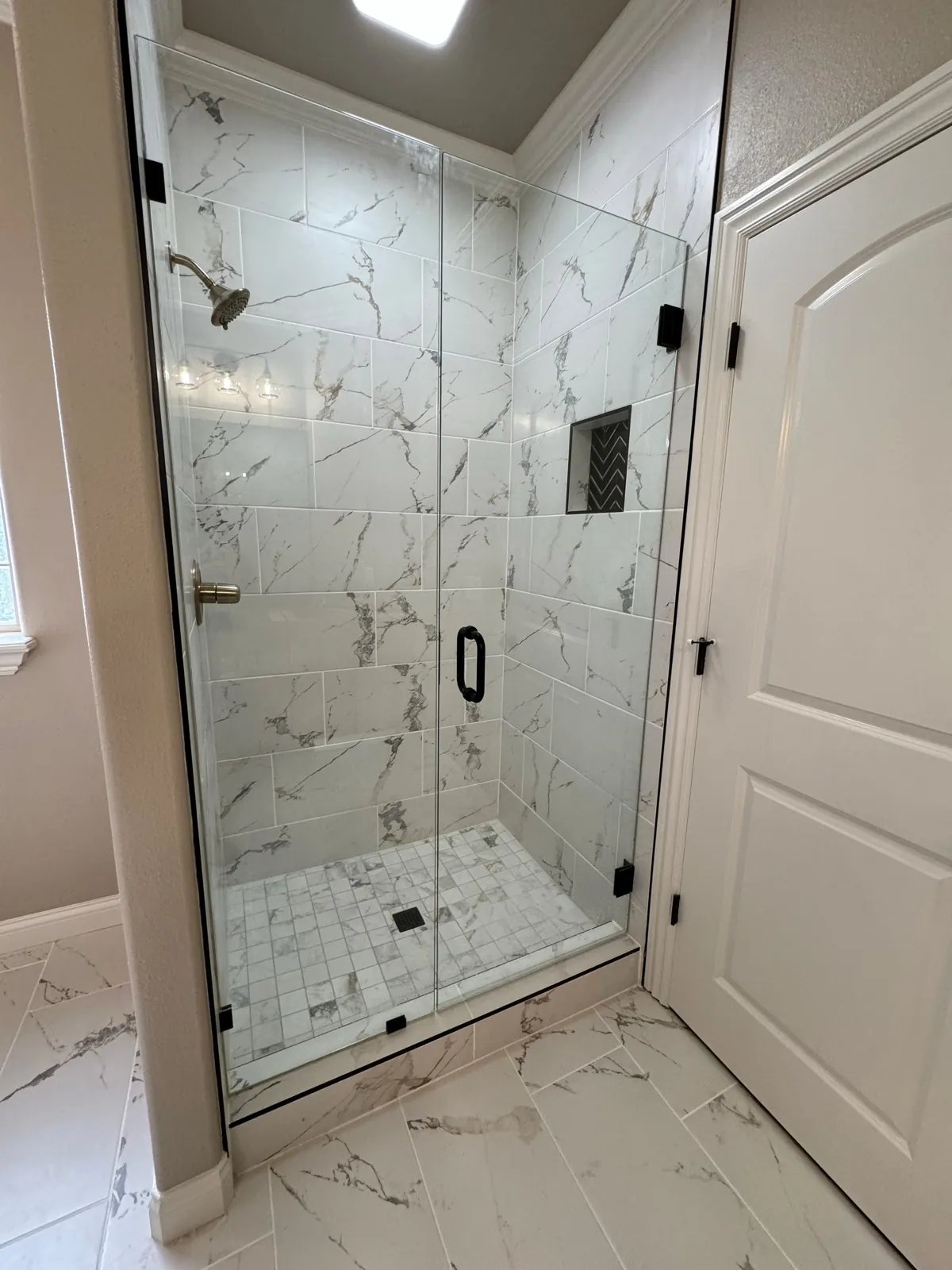 Frameless glass shower with marble subway tile