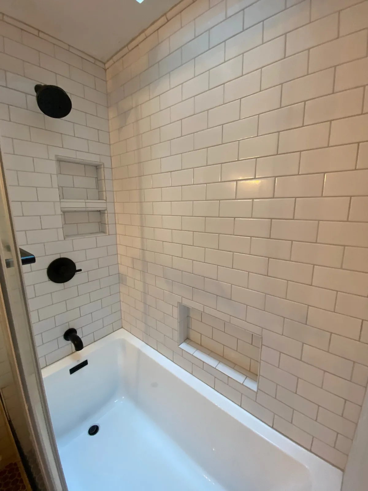 White subway tile tub shower with tile niche